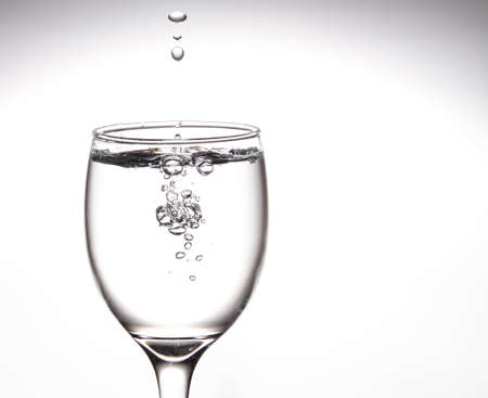 A tall glass, a glass of wine with clear water with bubbles floating in the mouth of the glass Inside on a gray backgroundの写真素材