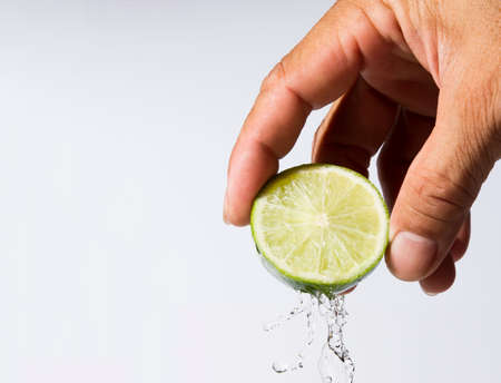 Man's hand squeezes the lemon slices until the water spreads on a white background.の写真素材