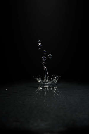 Beautiful water droplets fall on the ground until water splashes. Black background.の写真素材