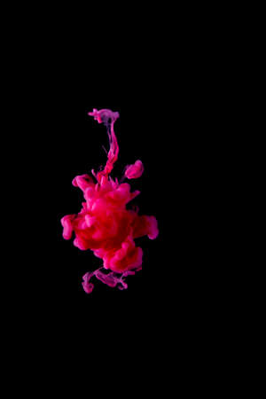 Red acrylic ink is scattered in the water, creating strange shapes. on a black background abstract backgroundの写真素材