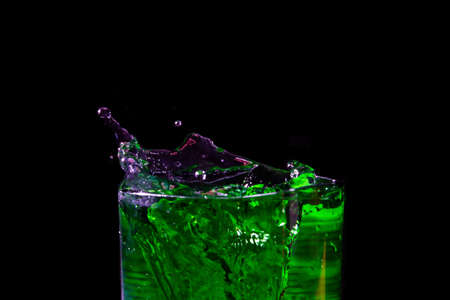 Water splashed from the mouth of the green glass. showing freshness on a black background