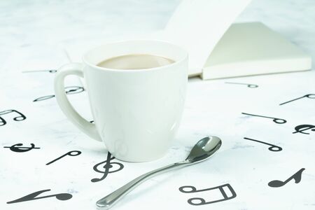 Coffee cup and book placed on the floor, musical note pattern