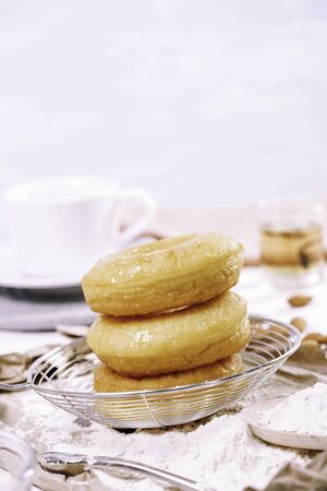Homemade fried donuts or cronuts in stack with sugar standing on crumpled paper over white wooden concrete table, leaving space for textの写真素材