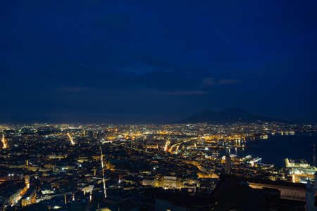 Skyline of Naples at night, with the city illuminated, and the silhouette of the Vesuvius volcano.の写真素材