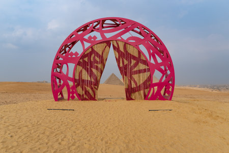 Sculpture in the middle of the desert, with the pyramids of Giza just behind.のeditorial素材