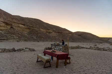 Man having a barbecue in a Bedouin village, in the Hurghada desert, at sunsetのeditorial素材
