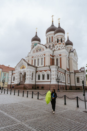Alexander Nevsky Cathedral in the city of Tallinn. A girl closing a green umbrella while it stops raining.のeditorial素材