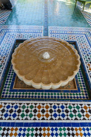 Fountain of the Secret Garden of the city of Marrakech. White fountain with blue and green mosaic...