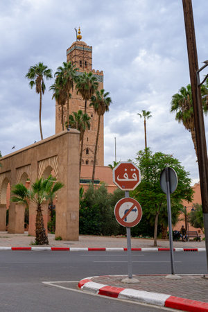 Photo of the tower of the Koutoubia Mosque. In the photo there is a stop sign written in Arabic. Cloudy day.の写真素材