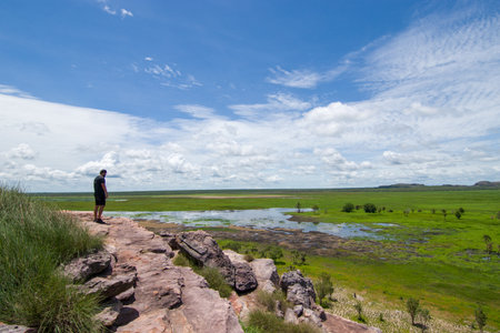Man standing on the edge of a cliff and looking at the lakeの写真素材