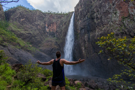 Man with arms outstretched standing in front of a waterfall in Hawaiiの写真素材