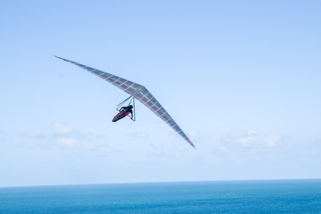Hang glider flying in the blue sky over the sea.の写真素材