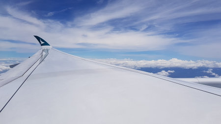 Wing of an airplane flying above the clouds in the blue sky.の写真素材