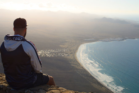 Man sitting on top of the mountain and looking at the sea.