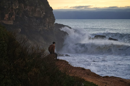 Man watching the waves at sunset on the ocean coast in Portugal.