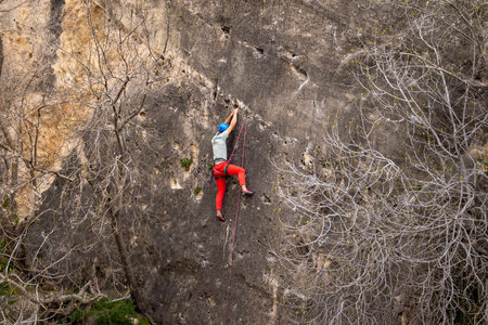 A woman climbs a rock. A climber overcomes a difficult route on a natural terrain. Extreme hobby.の写真素材