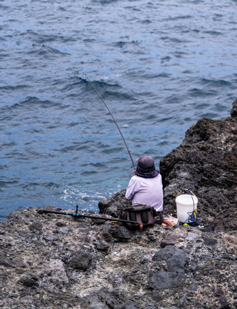 Fisherman fishing on a rock in the Mediterranean Sea in Sicilyの写真素材