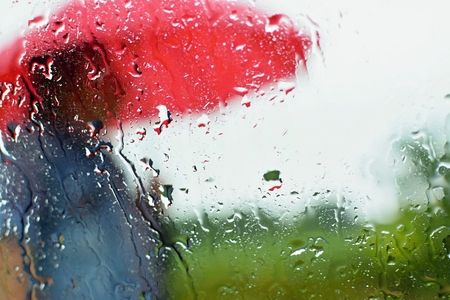 A man under an umbrella in the rain. Drops with a blurred background.の写真素材