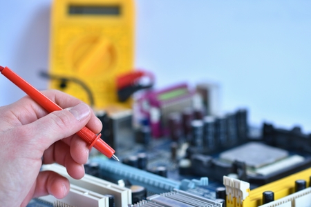 Hand with voltmeter clips above board with componentsの写真素材