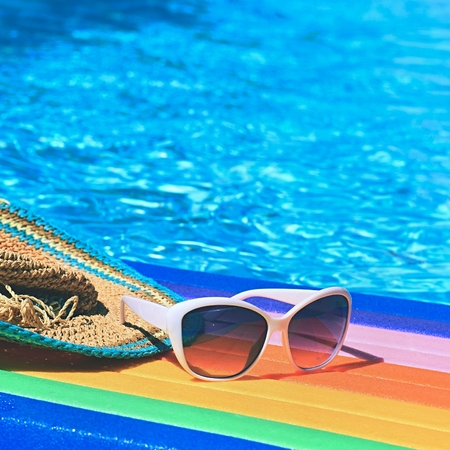 Sunglasses, lilo and hat on the water in hot sunny day. Summer background for traveling and vacation. Holiday idyllic.の写真素材