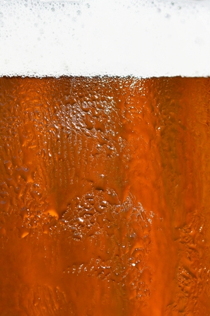 Beer. Beautiful detail of beaten glass of beer with foam. Abstract colorful background.