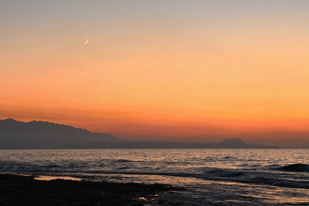 Beautiful summer sunset by the sea. Amazing scenery on the beach with waves and reflection of the sun. Background for holiday and vacation travel. Greece Crete Island.の写真素材