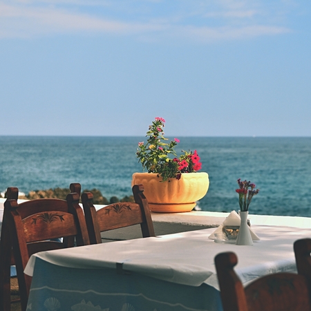 A covered table in a Greek tavern and a sea. Summer background for travel and holidays.の写真素材