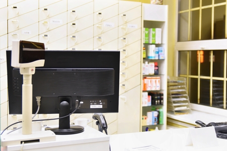 Cash desk - computer and monitor in a pharmacy. Interior of drug and vitamins shop. Medicines and...