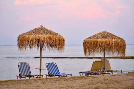 Beautiful morning - sunset and parasols and deck chairs on the beach by the sea.の写真素材