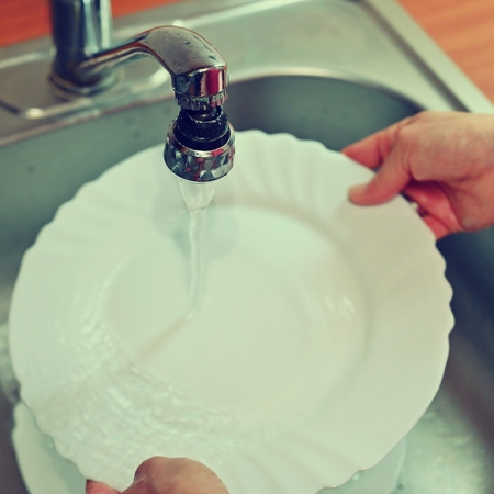 Hand washing dishes. Hand with sponge and sink in kitchen washing dirty dishes - plate.の写真素材