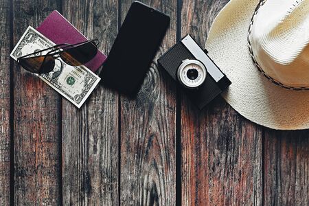 Items for summer vacation: a camera, passport,smartphone, money, hat, sunglasses. Wooden background, top view with Copy space. Beautiful summer concept for travel and summer vacation.の写真素材