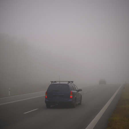 Bad weather driving - foggy hazy country road. Motorway - road traffic. Winter time.の写真素材