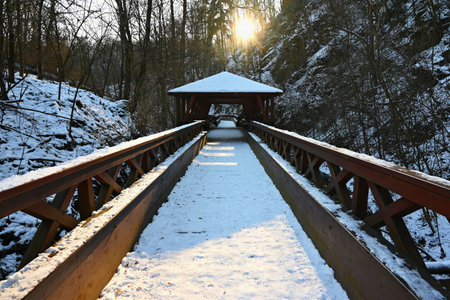 Beautiful snowy wooden bridge with a path for hiking. Winter season with snow and sun.の写真素材