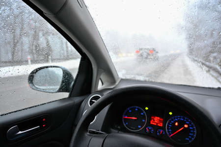 Dangerous winter season with snow on the road. The interior of the car from the driver's point of view - dangerous traffic in bad weather.の写真素材