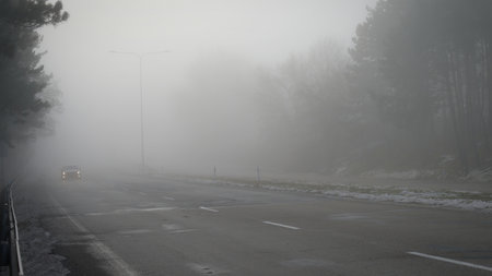 Cars in the fog. Bad winter weather and dangerous automobile traffic on the road. Light vehicles in fog.の写真素材