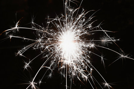Christmas background. A sparkler on a Christmas tree in the evening outside with snow. Concept for winter season, holidays and new year 2023.の写真素材