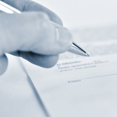 Closeup of a female hand signing a contract with a silver penの写真素材
