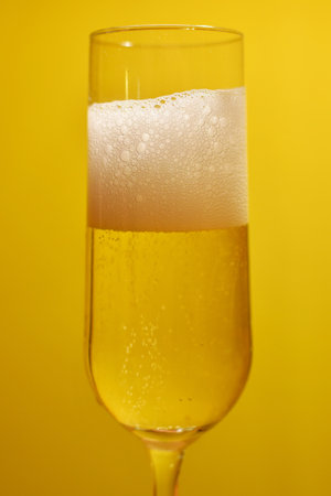 Champagne in a glass on a yellow background, close-up