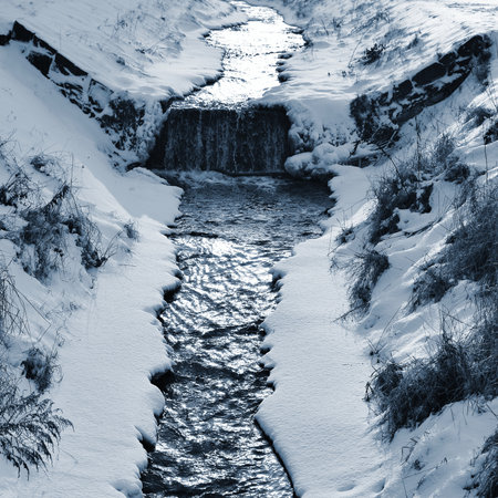 Winter landscape with a waterfall and a river. Blue toned.の写真素材