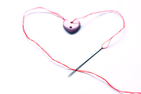 heart with red thread and needle on white background, valentine conceptの写真素材