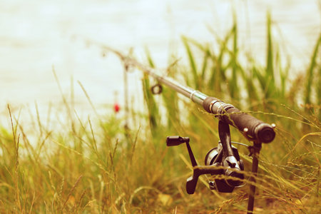 Fishing rod with reel on the background of the river and grassの写真素材