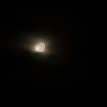 Full moon over dark black sky at night. Mysterious concept with clouds, fog and moon.の写真素材