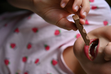 Young girl - child eating candy and sweets. Detail of face and mouth. Concept for healthy lifestyle - healthy - unhealthy sweet food and sugar.の写真素材