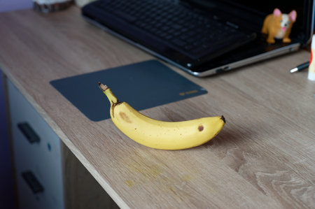 A beautiful fresh banana on a work table at home or in the office with a computer or laptop.の写真素材
