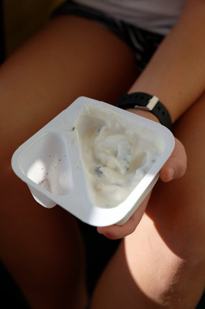 ice cream in a plastic cup on the hands of a girl.