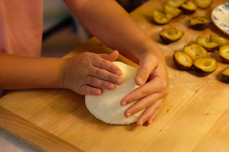 Child's hands knead the dough on a wooden cutting board.の写真素材