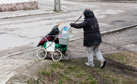 old homeless woman pushing a broken stroller