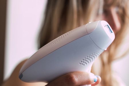 young blond woman holding a appliance for photo-epilationの写真素材
