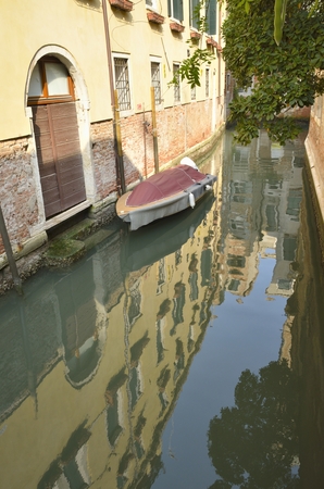 Reflections of buildings on a narrow canal in Venice Italyの写真素材
