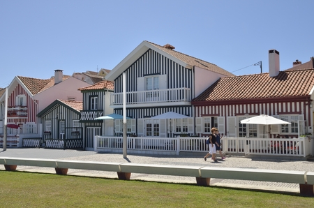 Two women walking along traditional beach houses in  colored stripes in Costa Nova, Portugal.
These traditional structures were used by fishermen to store their fishing materials.のeditorial素材